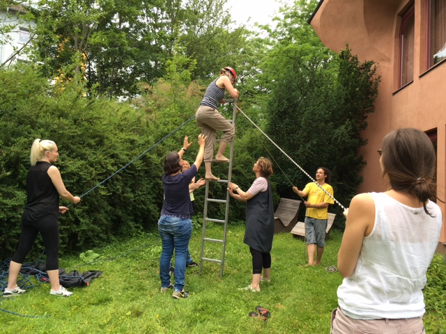 Teamwork - Menschen halten eine Leiter, eine Person steigt auf die Leiter