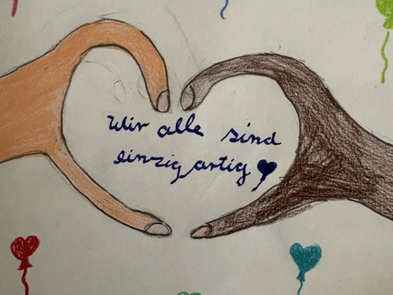 Zwei gezeichnete Hände (eine hell, eine dunkel) formen ein Herz. In der Mitte steht: Wir sind alle einzigartig.