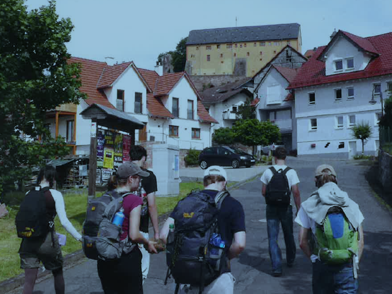 Schüler:innen mit Rucksäcken wandern eine Straße entlang